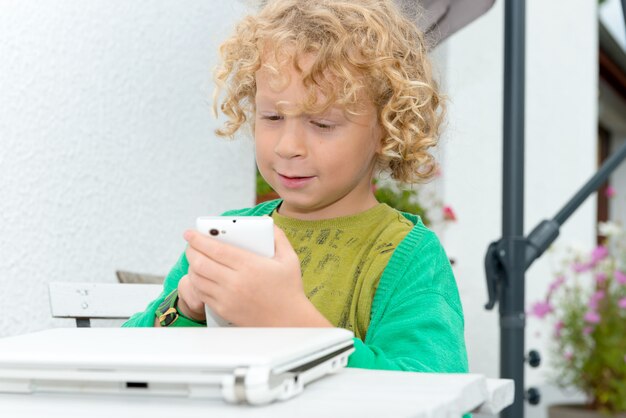 Portrait of a little blond boy using a smartphone