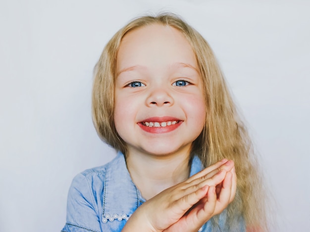 Ritratto di una piccola bambina bellissima dagli occhi azzurri, su sfondo bianco