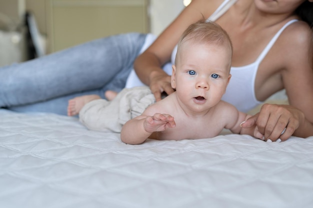 生後4ヶ月の男の子の肖像画。彼は母親の隣のベッドに横たわっている。テキストの場所。