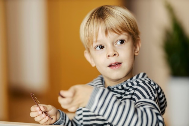 Портрет маленького мальчика, отводящего взгляд во время игры с развивающей игрушкой в детском саду