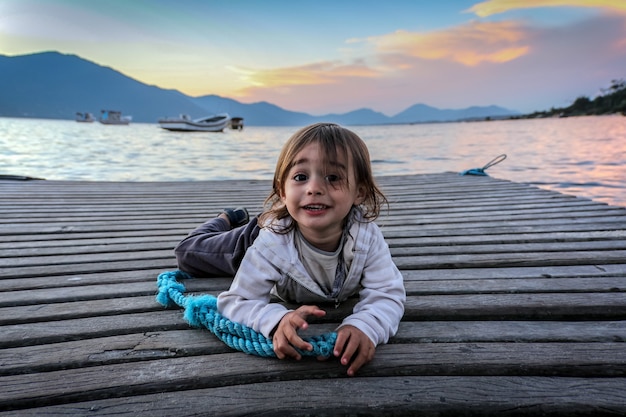 Portrait of a little boy looking towards the camera lying on a pier