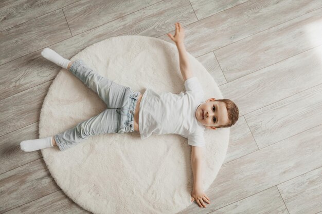 Portrait of a little boy lying on a carpet underfloor heating at home