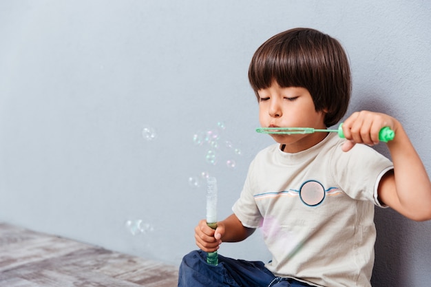 Portrait of little boy playing and blowing soap bubbles