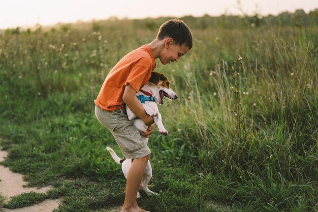 Foto ritratto di un ragazzino che gioca con il suo cane jack russell nel parco