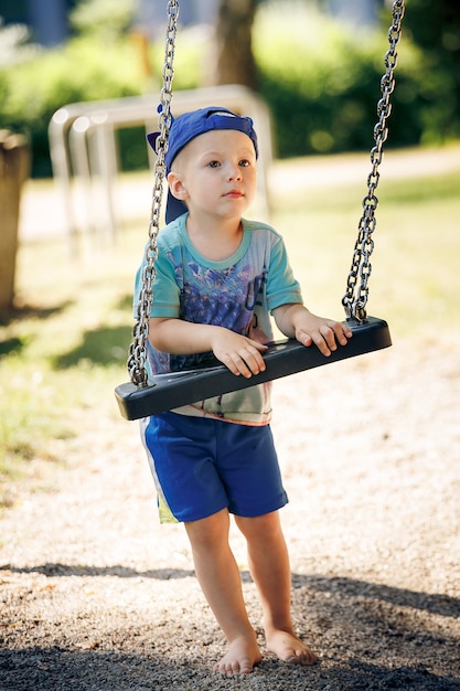 Photo portrait of little boy playing with swing at park