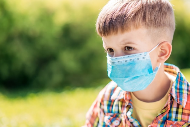 Portrait of a little boy in a protective mask on the street during the coronavirus and Covid pandemic - 19