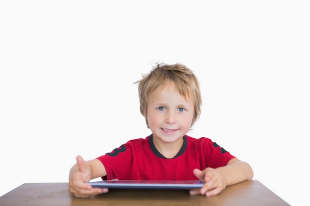 Portrait of little boy sitting at desk with digital tablet