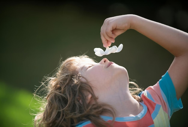 Портрет маленького мальчика, нюхающего цветок плюмерии, концепция детского лица крупным планом, стреляющего в голову детям пор