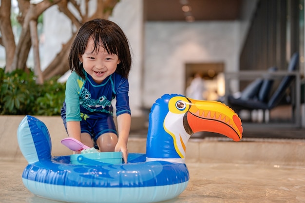 Portrait of little boy in swimming pool on funny inflatable hornbill float ring learning swim