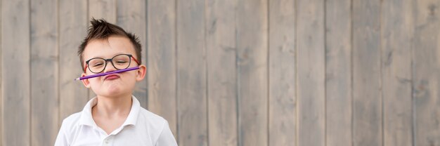 Portrait of little boy wearing glasses and white T-shirt at wooden surface