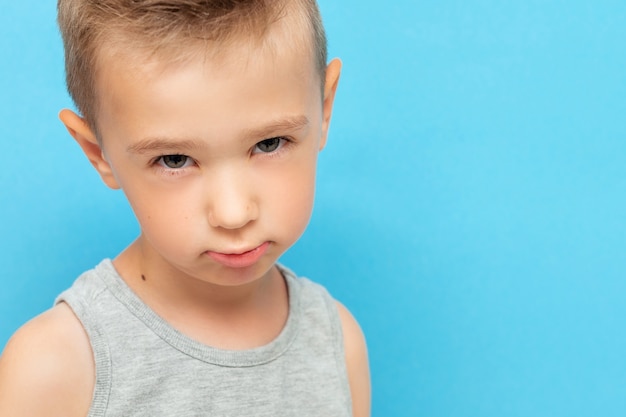 Portrait of little boy with expression on his face with suspicion and surprise on blue