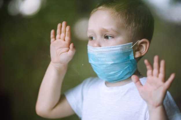 Portrait of little boy with medical face mask looking at camera in the city