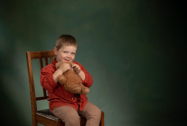 Portrait of little boy with teddy bear on green background