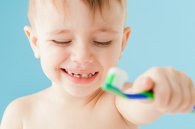 Portrait of little boy with toothbrush on blue.