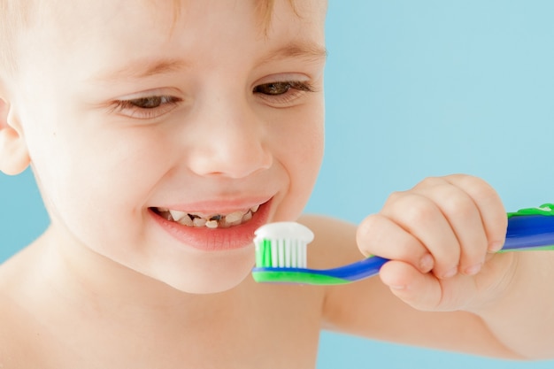 Portrait of little boy with toothbrush on blue.