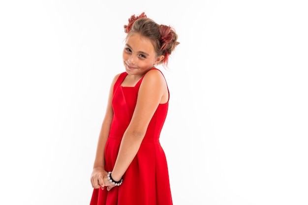 Photo portrait of little caucasian girl with fair hair and pretty face in red dress smiles and rejoices