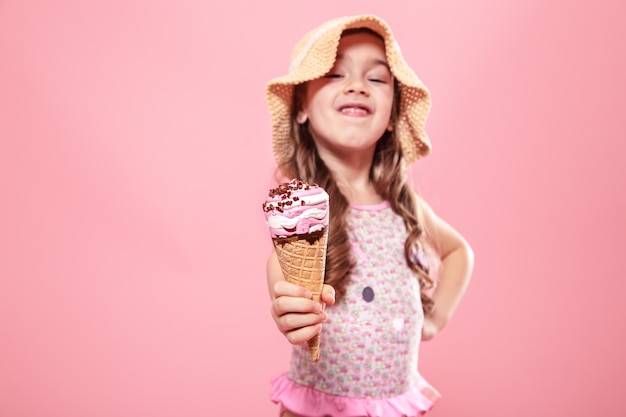 Portrait of a little cheerful girl with ice cream on a colored wall