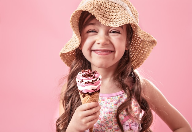 Portrait of a little cheerful girl with ice cream on a colored wall