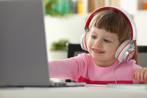 Portrait of a little child girl in headphones with laptop