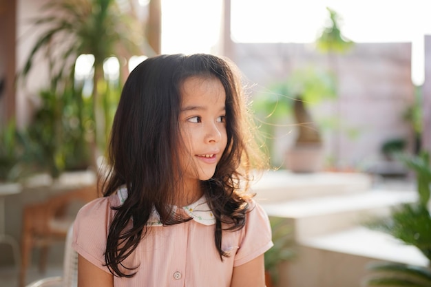 웃 고 카메라를 보고 어린 아이의 초상화. 카페에서 즐기는 웃는 아시아 소녀.