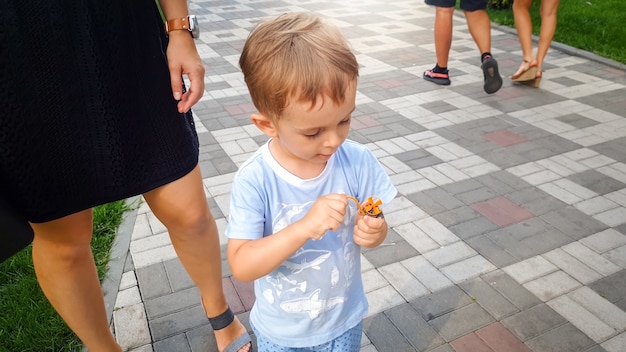 Portrait of little concentrated toddler boy playing with toy helicopter in park