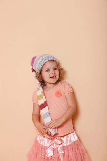 Portrait of little curly girl in the winter colorful hat posing for photo