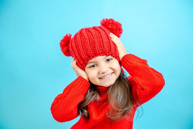 冬のニットの赤い帽子をかぶった小さな縮れ毛の少女の肖像画黒髪の少女