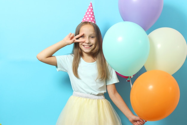 Portrait of a little cute girl in a festive cap and with balloons