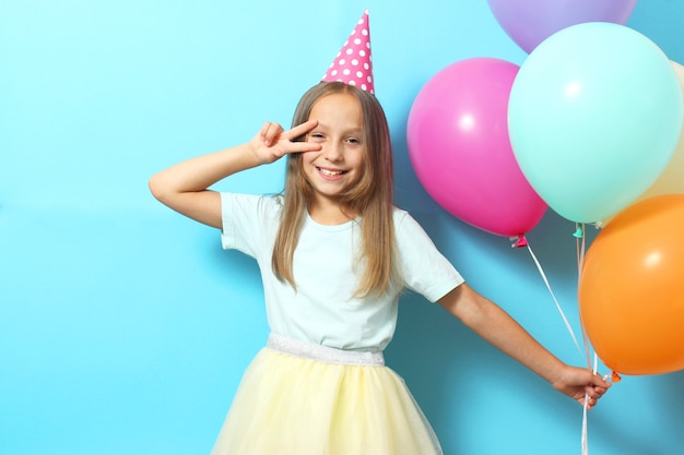 Portrait of a little cute girl in a festive cap and with balloons