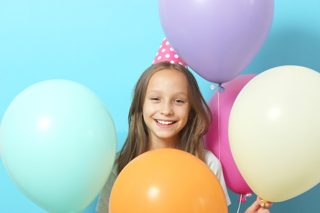 Portrait of a little cute girl in a festive cap and with balloons