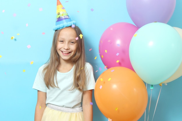 Portrait of a little cute girl in a festive cap and with balloons