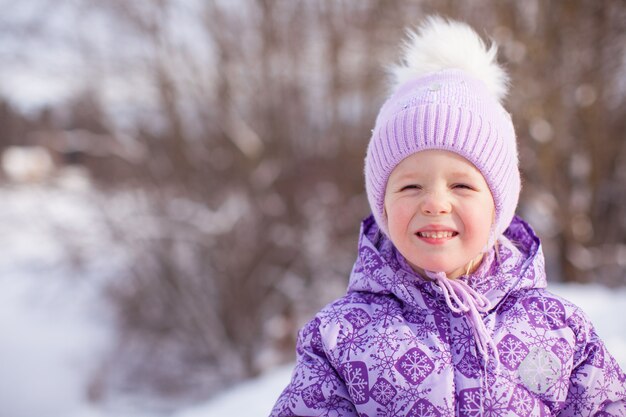 Portrait of little cute happy girl in snow sunny winter day