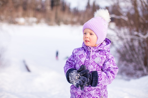 Portrait of Little cute happy girl in the snow sunny winter day