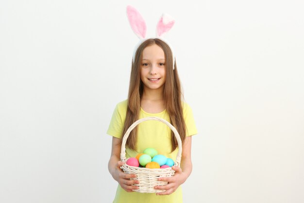 Portrait of a little cute smiling girl with bunny ears and easter eggs in hands