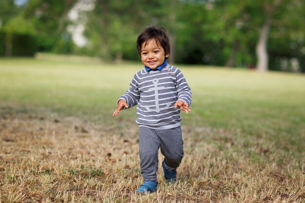 Portrait of a little eastern handsome baby boy playing outdoor in the park. Arabian child fun on the street.