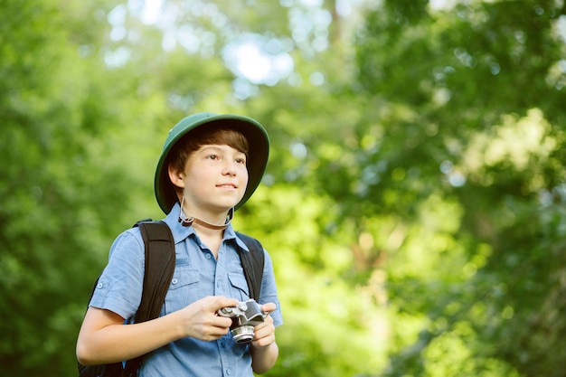 Portrait of little explorer with photo camera in forest