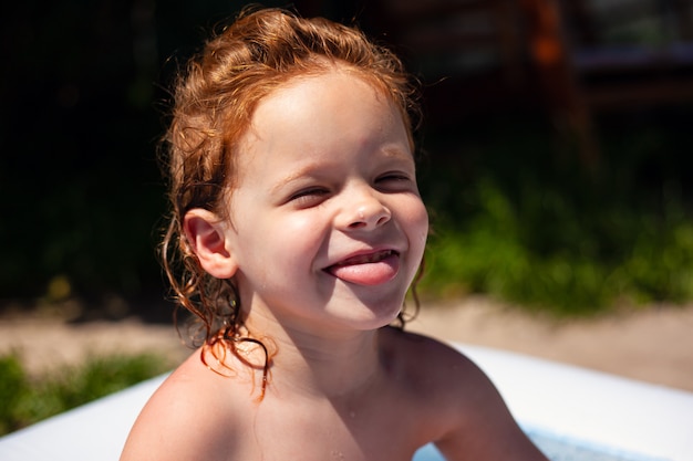 Portrait of a little ginger girl swimming in the pool.