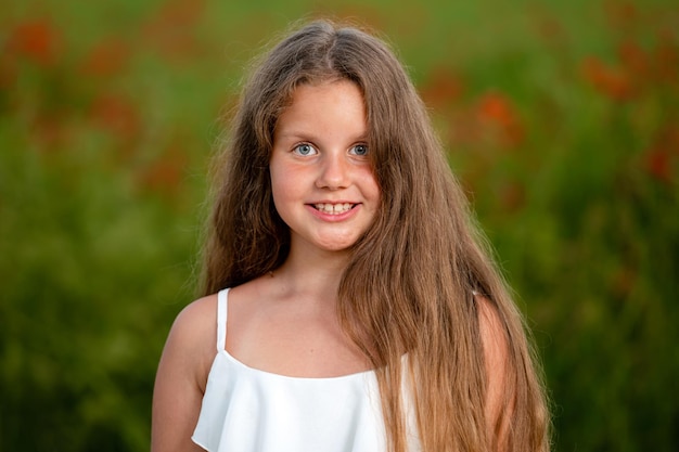 Portrait of a little girl against the background of a field of poppies in the evening sunlight