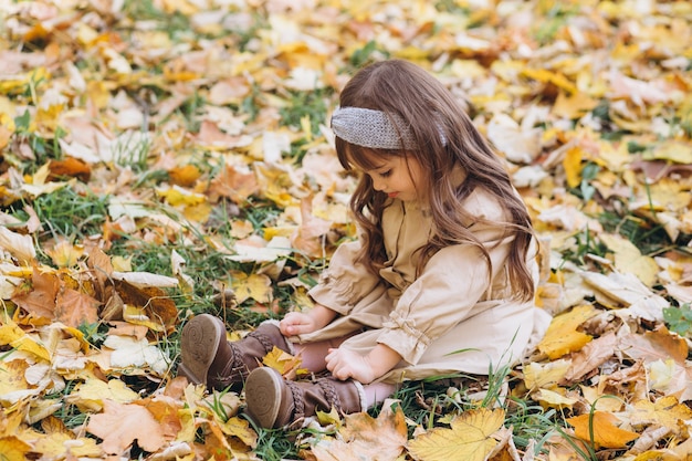 portrait little girl in a beige coat walks in the autumn park