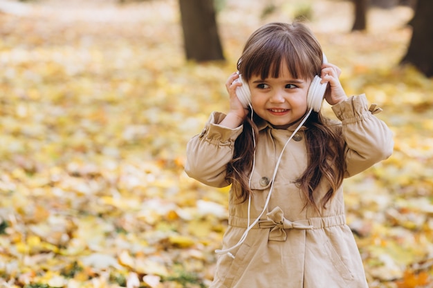 ベージュのコートを着た肖像画の少女が秋の公園を歩く