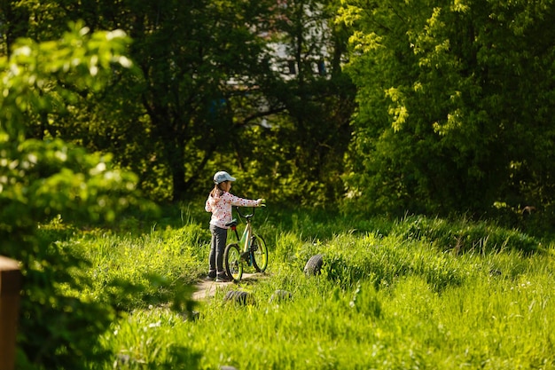 屋外の夏の公園で自転車に乗っている少女の肖像画