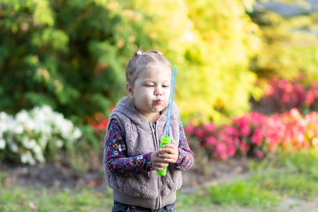 Portrait of the little girl blowing soap bubbles in the park