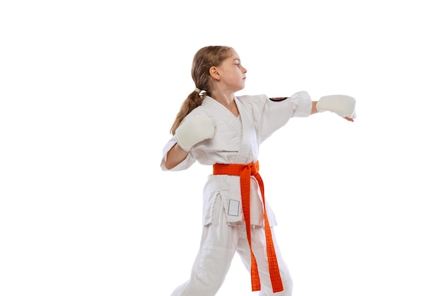 Portrait of little girl, child in kimono training karate isolated over white background.