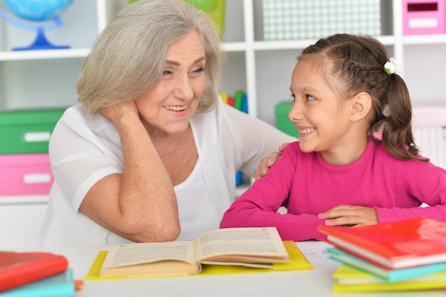 Portrait of little girl doing homework with her grandmother at home