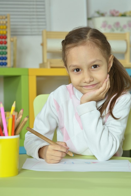 Photo portrait of little girl drawing at home