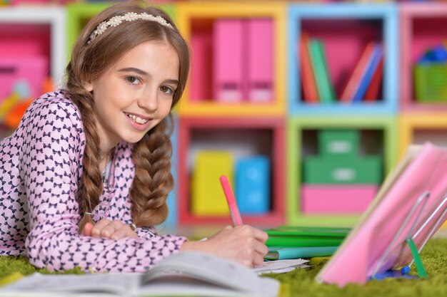 Portrait of little girl drawing with pencil in her room