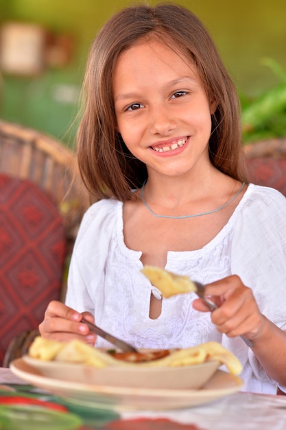 Photo portrait of little girl eating in cafe