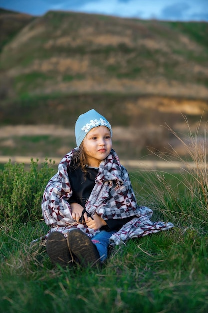 portrait of a little girl on an evening walk outside the city, wrapped in a plaid