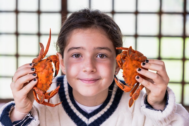 Portrait of a little girl having fun with two necoras in her hands to play with