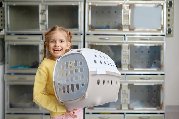 Portrait of little girl holding cage with new pet bought at veterinary shop